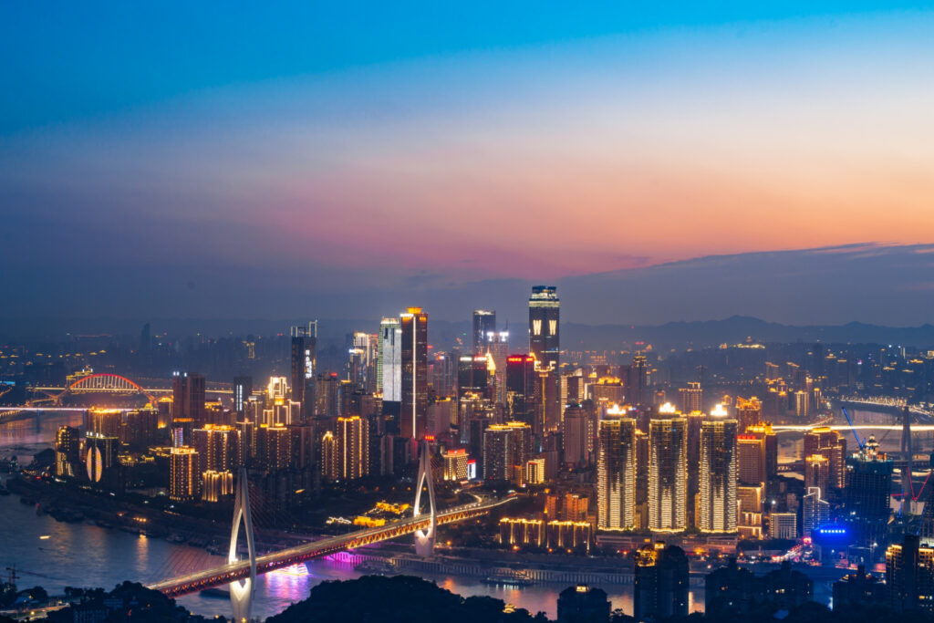 Shenzhen City skyline illuminated at night, with vibrant lights reflecting off towering skyscrapers and bustling streets below