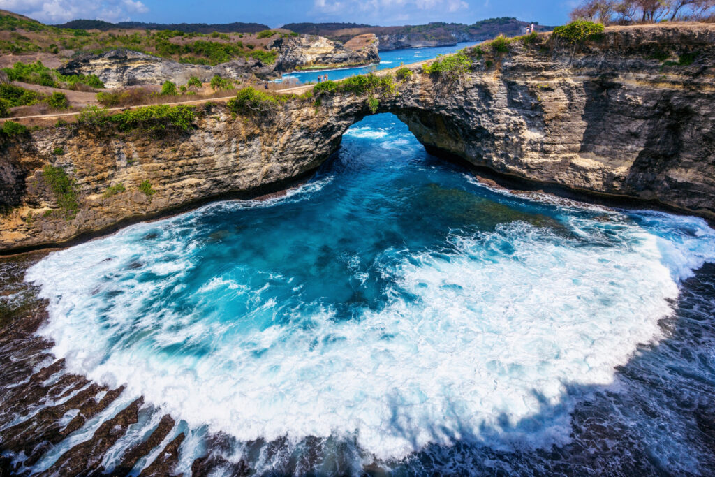 Aerial view of Broken Beach, a natural rock arch surrounded by turquoise waters and cliffs on Nusa Penida Island, Indonesia