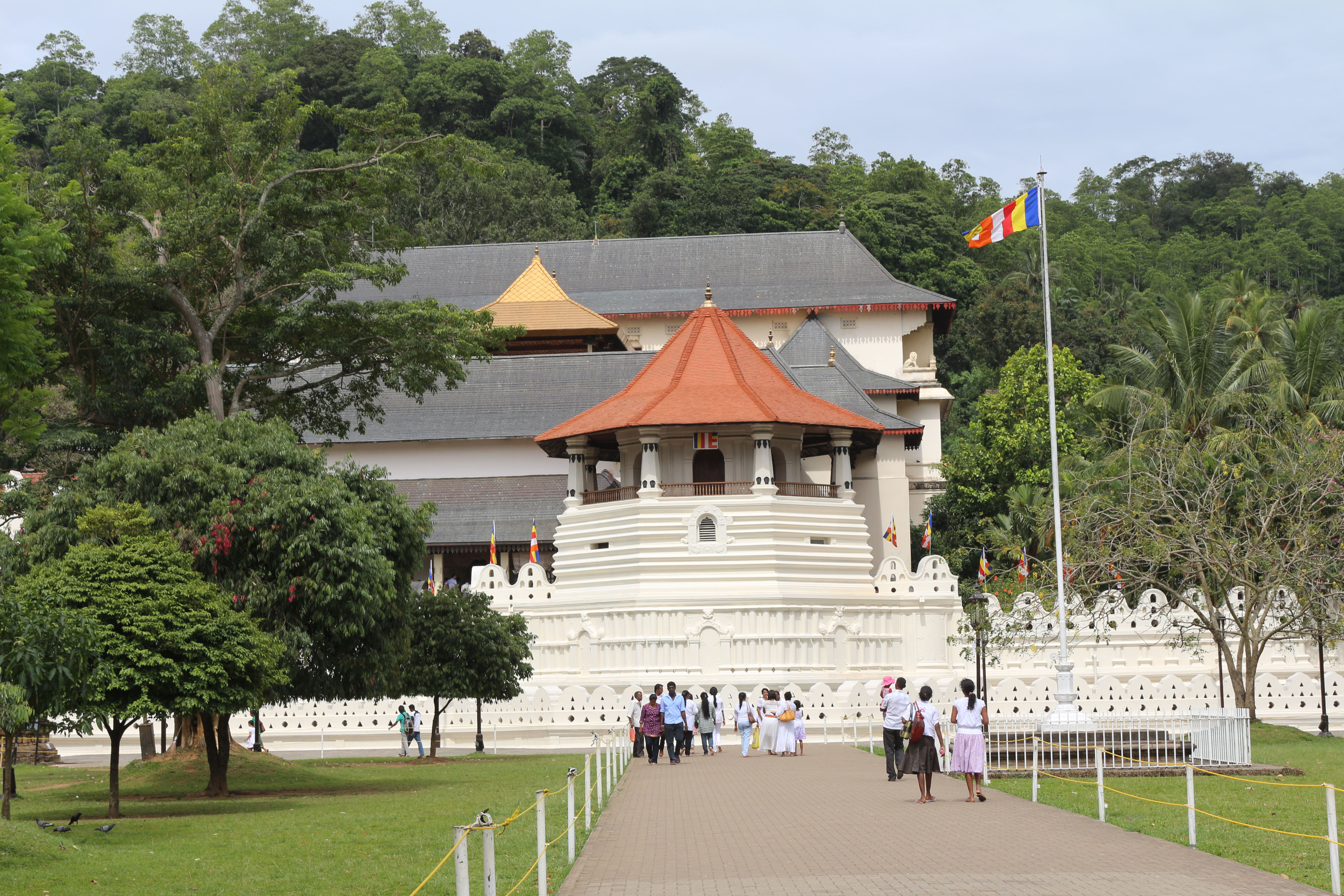 The front view of the Temple of the Tooth in Kandy, Sri Lanka, showcasing its ornate architecture and surrounding lush greenery