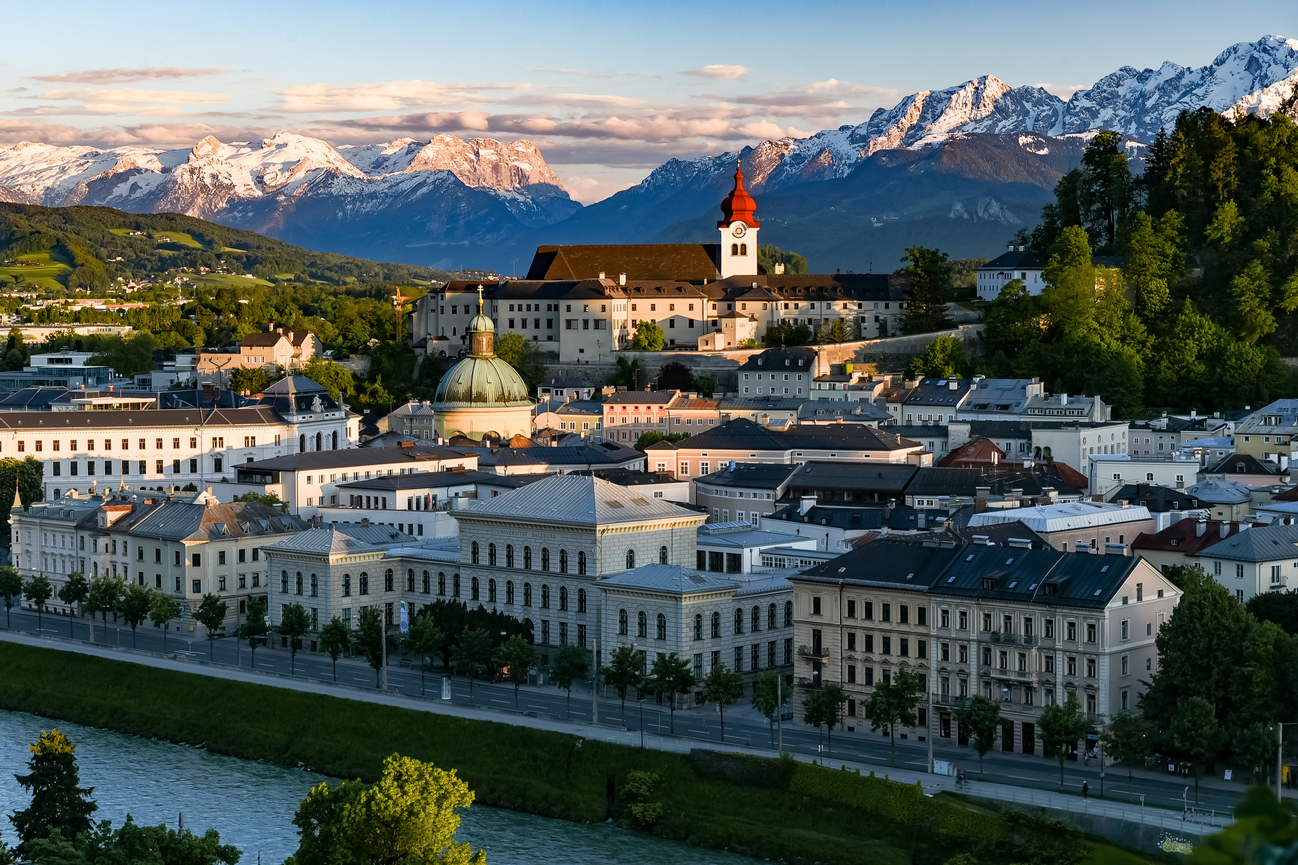An aerial view of Salzburg, Austria, showcasing Hohensalzburg Fortress, the historic Old Town, and the Salzach River.
