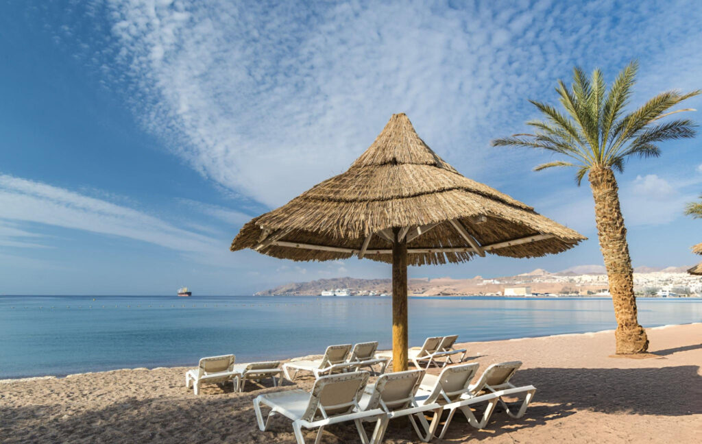 A scenic view of Eilat, a coastal city in Israel, featuring the turquoise waters of the Red Sea, sandy beaches, and a backdrop of modern buildings, popular among adventure seekers.