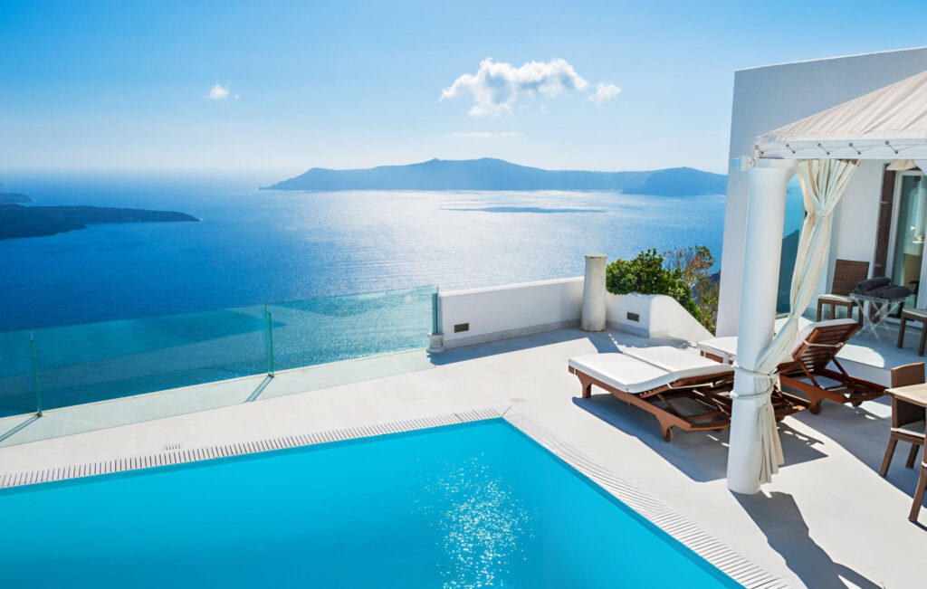 A luxury resort in Santorini, Greece, featuring whitewashed suites with private infinity pools overlooking the Aegean Sea, with the sun setting in the background