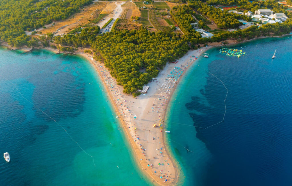A stunning aerial view of Bol, Croatia, showcasing the coastline, vibrant blue waters, and the charming town nestled among lush greenery