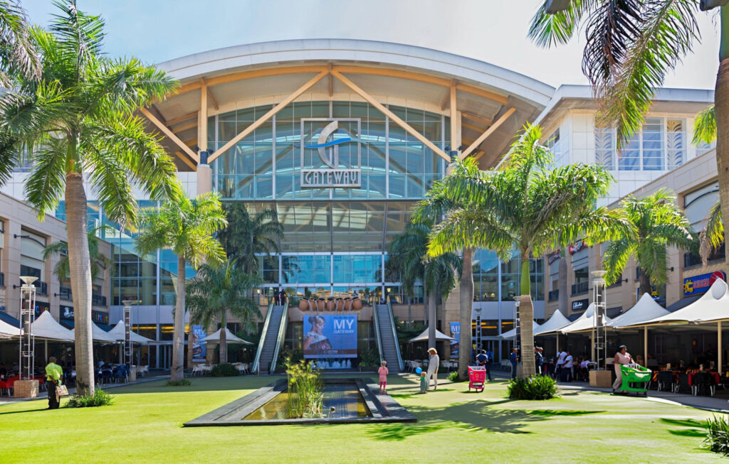 A bustling shopping area in Durban with vibrant market stalls, shops, and locals exploring the market