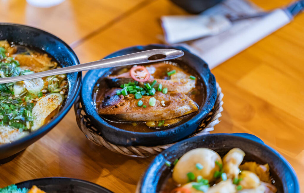 A vibrant plate of Banh Mi Xiu Mai, a Vietnamese baguette served with meatball soup, alongside fresh herbs and dipping sauce