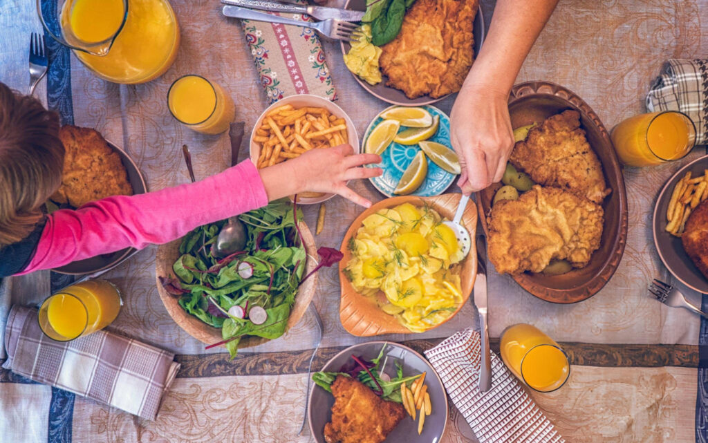 A beautifully plated dish of Wiener Schnitzel served with a lemon wedge and potato salad.