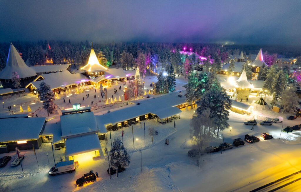 Panoramic view of Rovaniemi, Finland, covered in snow, with the Northern Lights glowing in the sky above the Arctic Circle