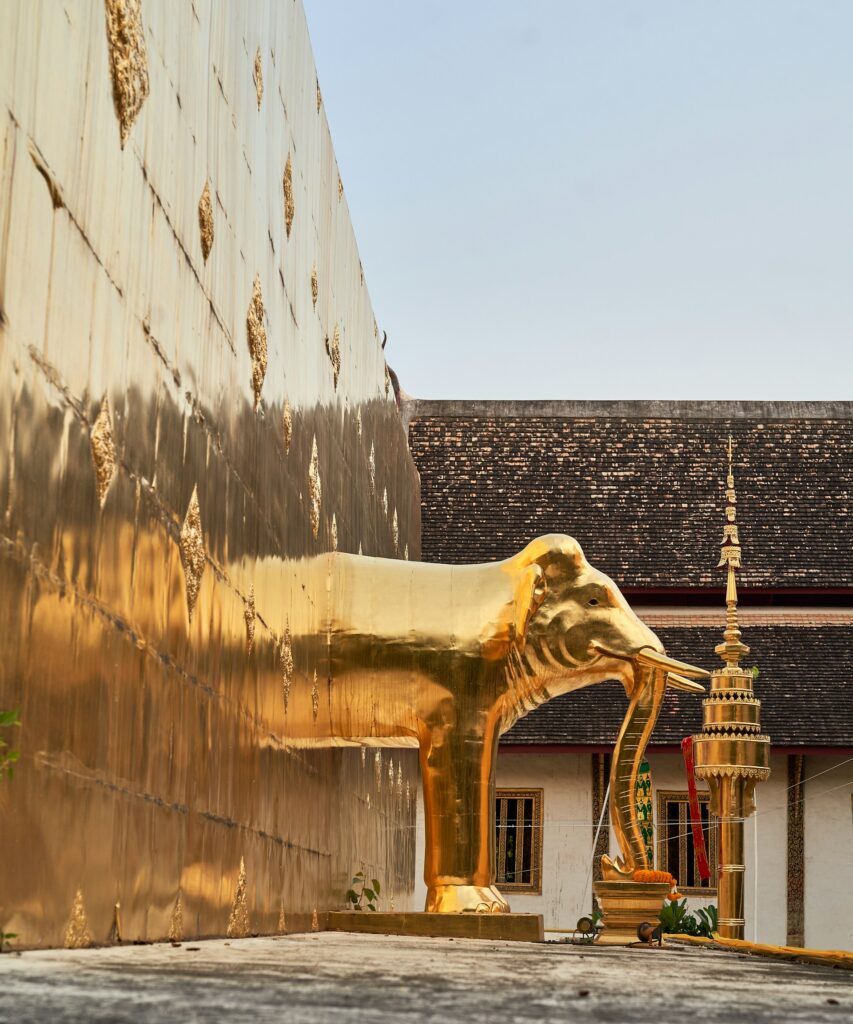Golden elephant statue at Wat Phra That Doi Suthep, gleaming against the backdrop of a traditional Thai temple