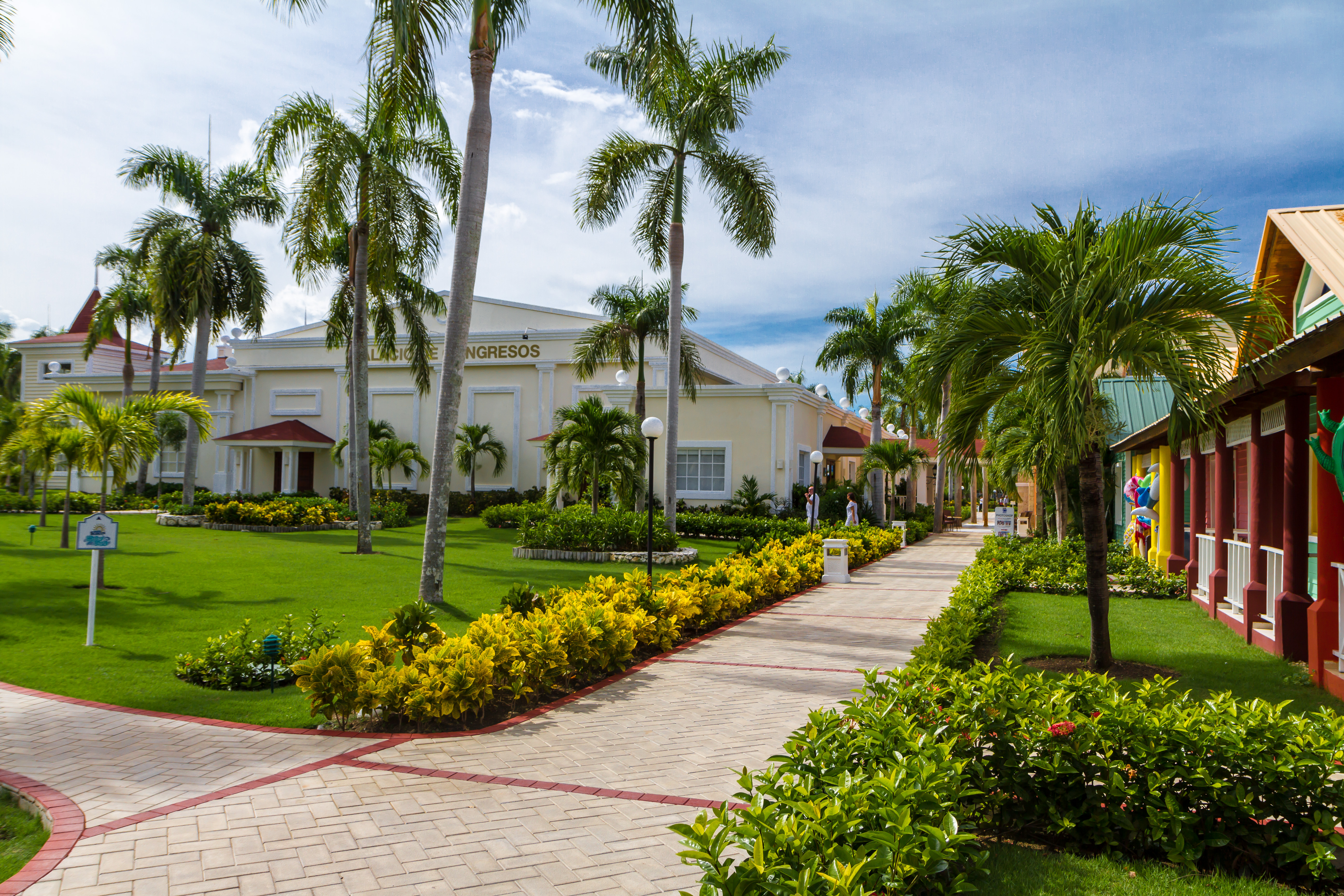 A luxurious resort in Bávaro, Dominican Republic, featuring a large swimming pool, palm trees, and beachside views with turquoise waters in the background