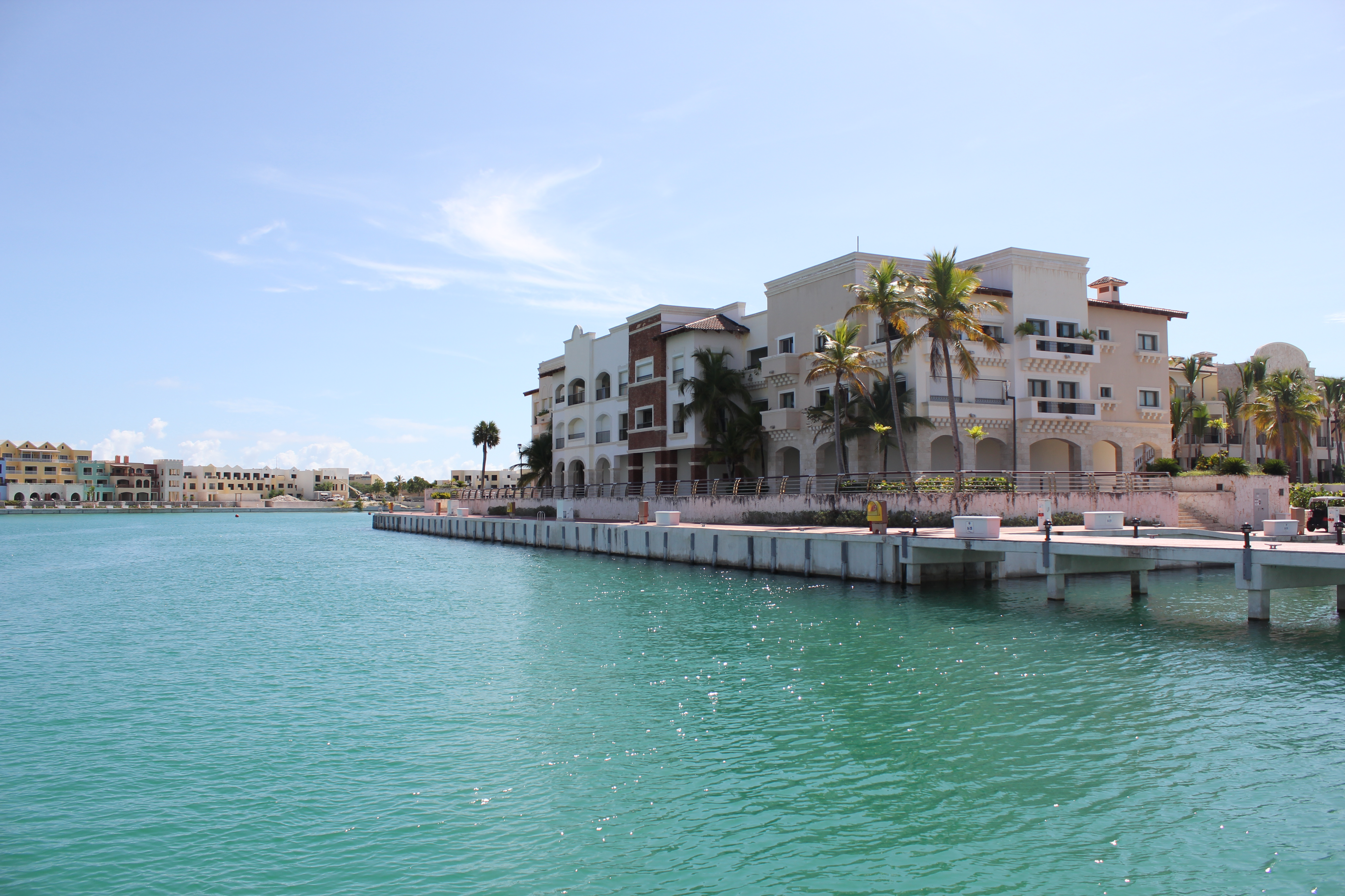 A scenic view of Cap Cana Marina in the Dominican Republic, featuring luxury yachts docked along the marina and elegant waterfront buildings