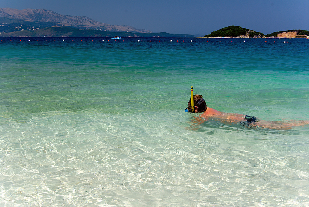 A girl snorkeling in the clear turquoise waters of Ksamil, exploring marine life