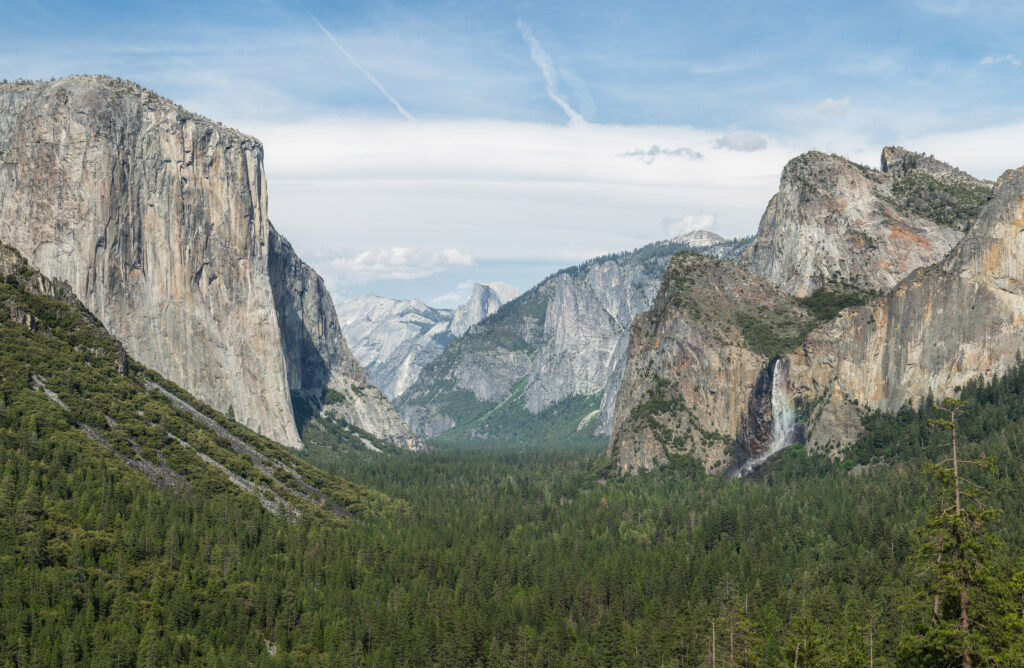 Tunnel View, Yosemite Valley, showcasing a panoramic view of El Capitan, Half Dome, and Bridalveil Fall surrounded by lush greenery