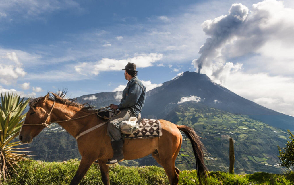 A man riding a horse through the mountains near Baños, Ecuador