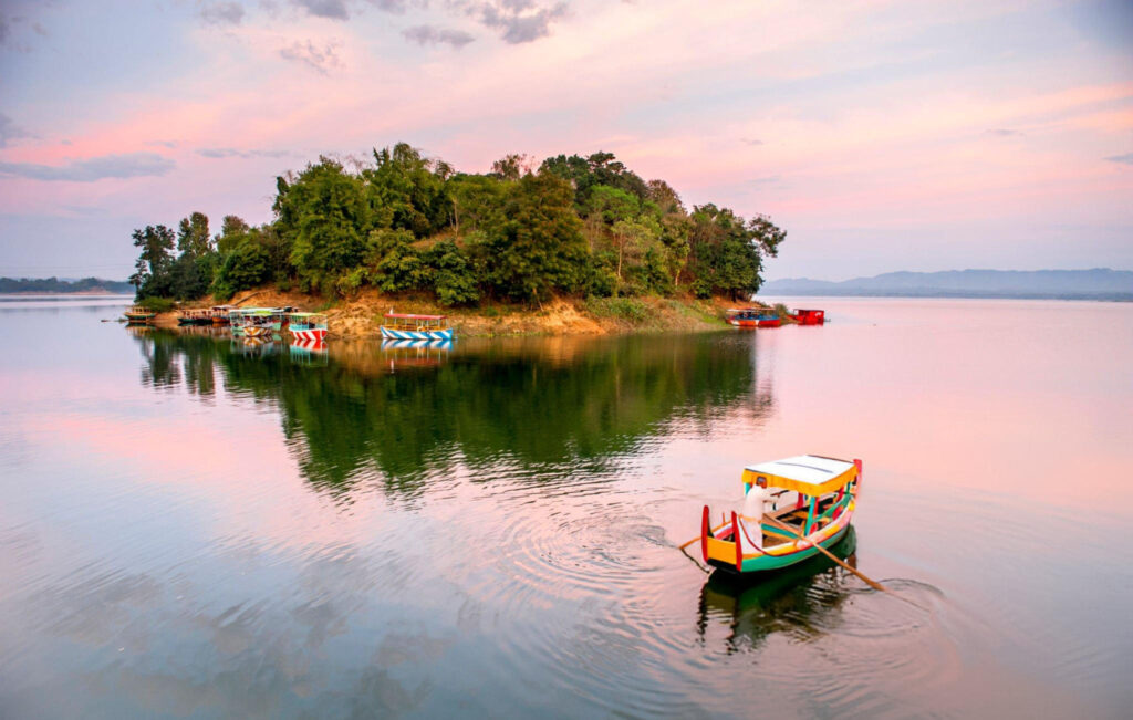A peaceful view of Kaptai Lake with small boats floating on the calm water, surrounded by green hills in Rangamati, Bangladesh.