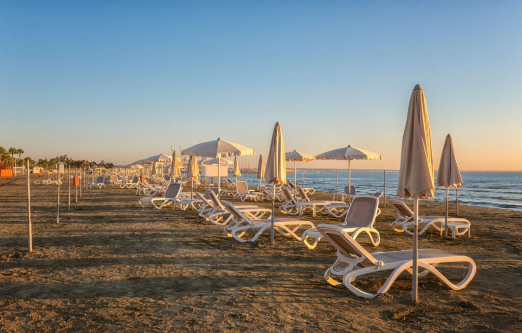 A scenic beach view in Larnaca, Cyprus, with golden sand, clear turquoise waters, and sun loungers under a blue sky