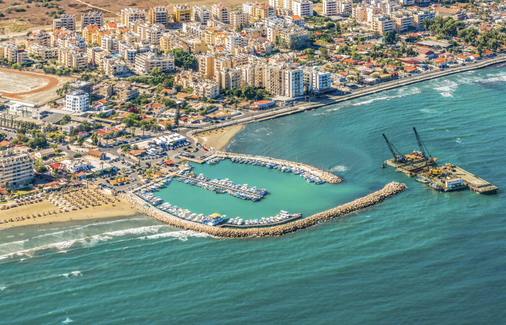 A panoramic view of Larnaca City, Cyprus, featuring the coastline, palm-lined promenade, and historical landmarks