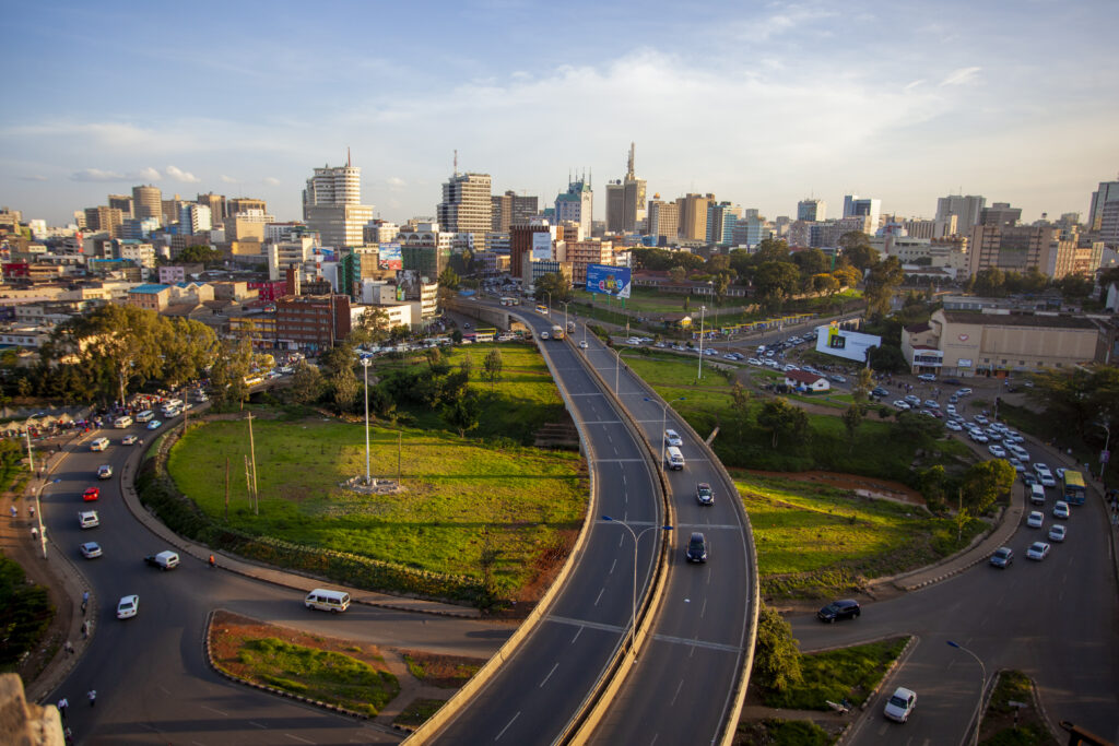 A panoramic view of Nairobi city with modern skyscrapers, lush greenery, and clear skies.