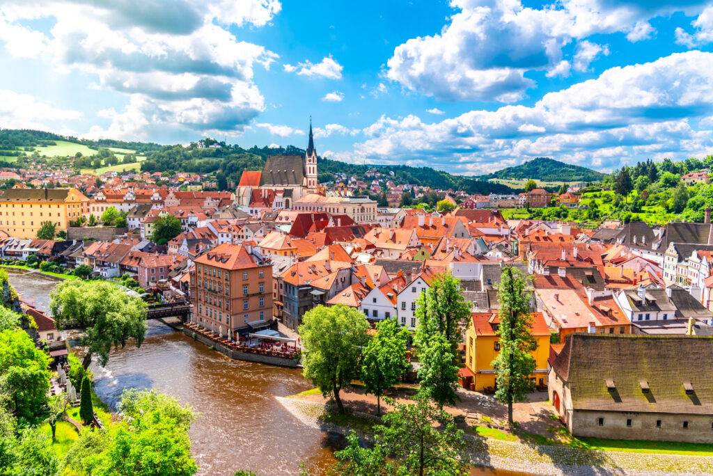 Panoramic view of Český Krumlov with St. Vitus Church in the center of the historical city, surrounded by traditional buildings and the scenic landscape of Southern Bohemia.