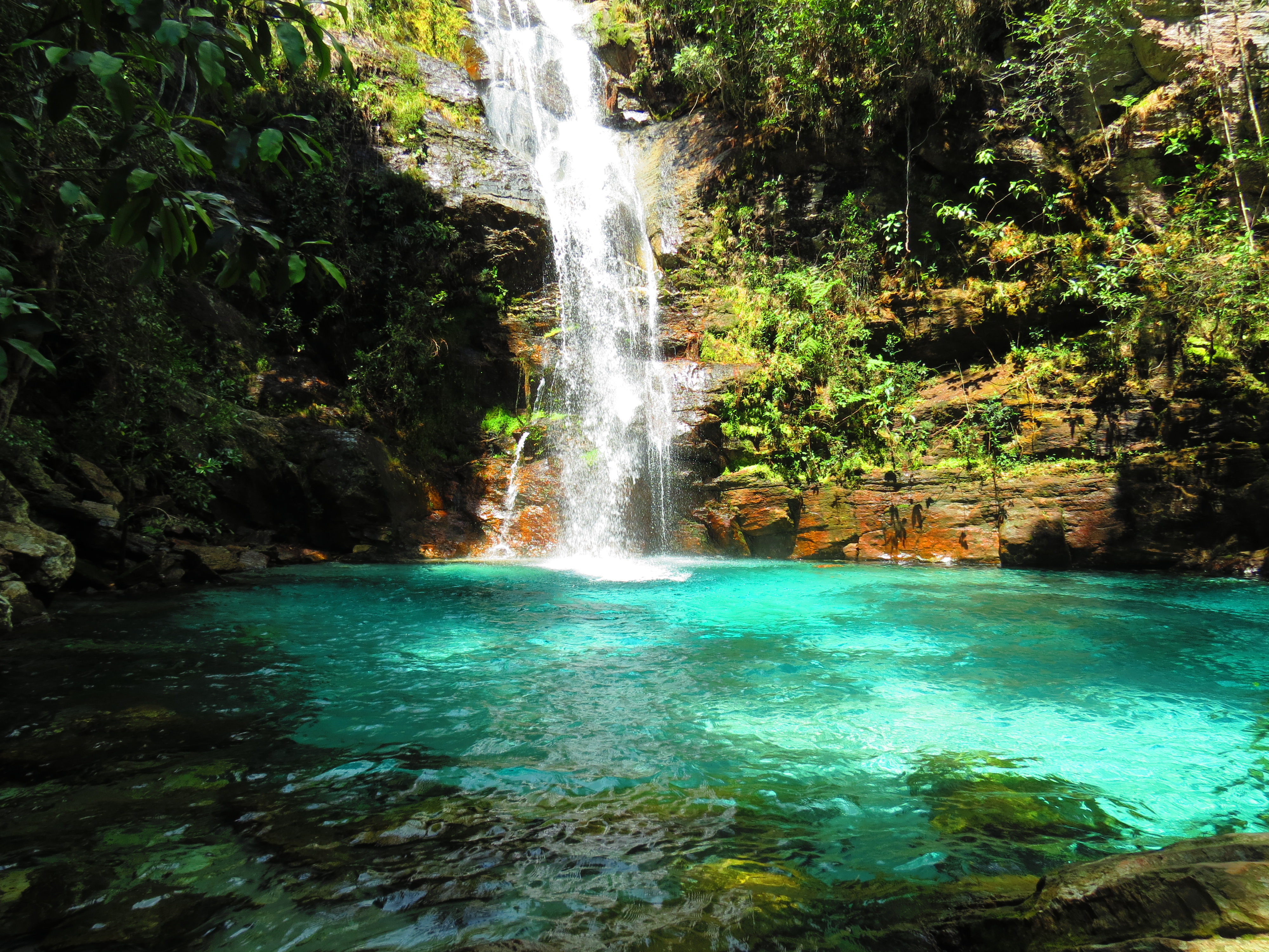 Waterfall cascading down rocky cliffs in Chapada dos Veadeiros Valley, Brazil, surrounded by lush green vegetation