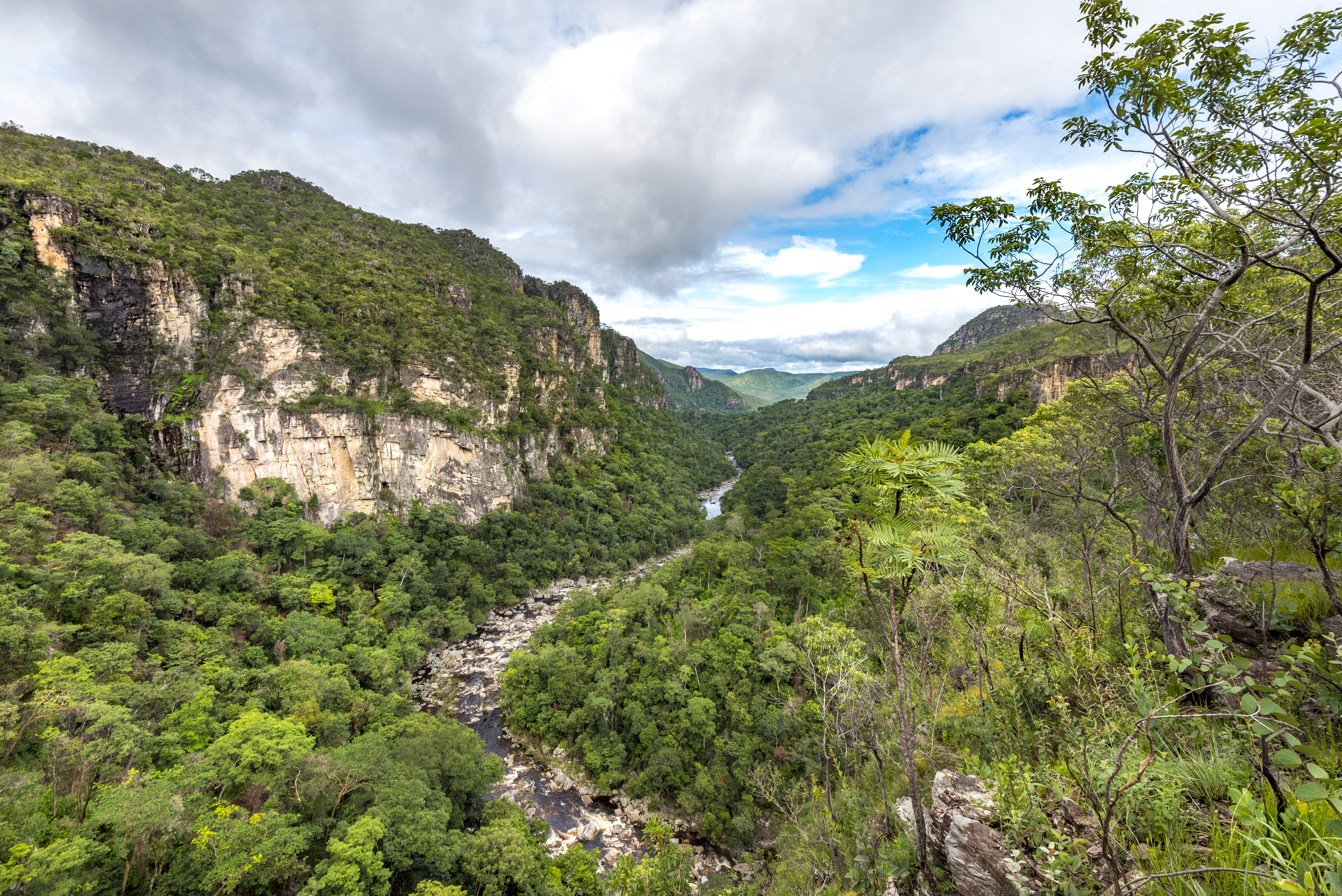 Overview of Chapada dos Veadeiros Valley in Brazil, showcasing rugged cliffs, lush vegetation, and winding rivers under a clear blue sky