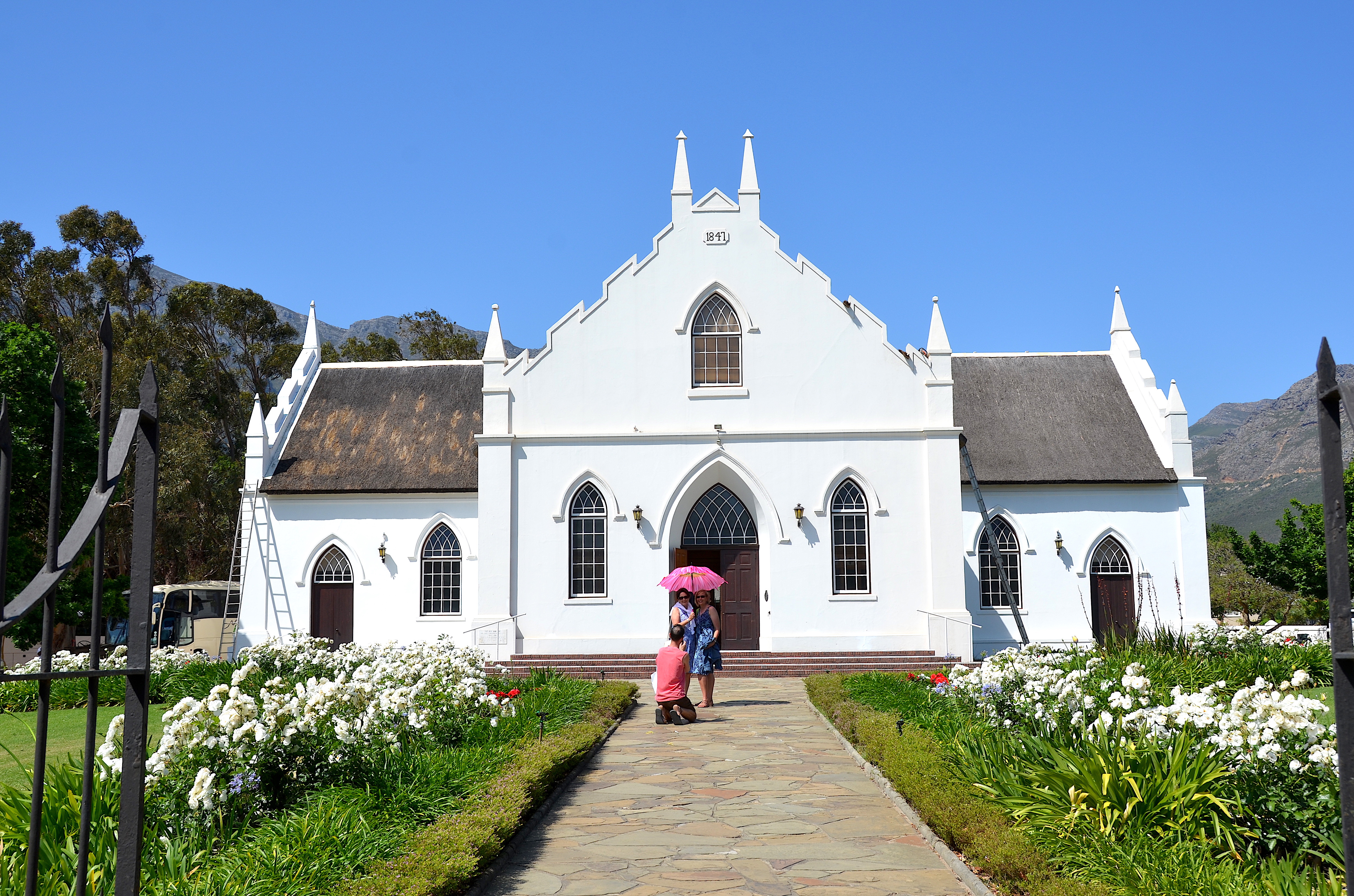 Dutch Reformed Church with Cape Dutch architecture, white facade, and scenic mountain backdrop in Franschhoek, South Africa