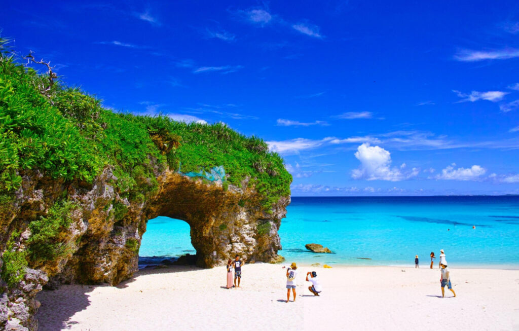 View of Sunayama Beach on Miyako Island, Okinawa, Japan, showcasing its iconic stone arch, white sand, and clear turquoise waters