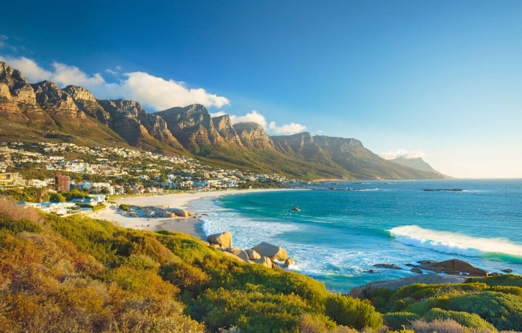 Camps Bay Beach with clear blue waters, white sand, and views of the Twelve Apostles mountain range in Cape Town, South Africa