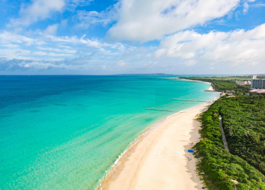 Aerial view of Yonaha Maehama Beach with white sand and turquoise waters, surrounded by lush green vegetation on Miyako Island, Okinawa, Japan