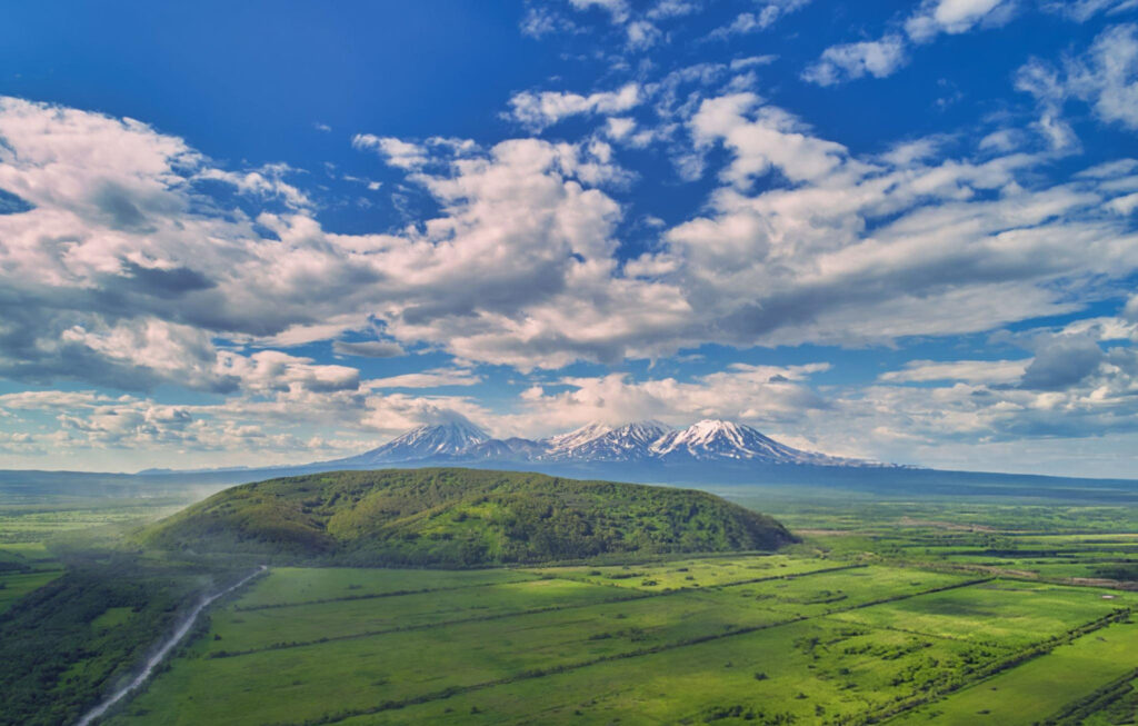 Kamchatka Valley of Geysers with erupting geysers, volcanic mountains, and geothermal springs in the distance.