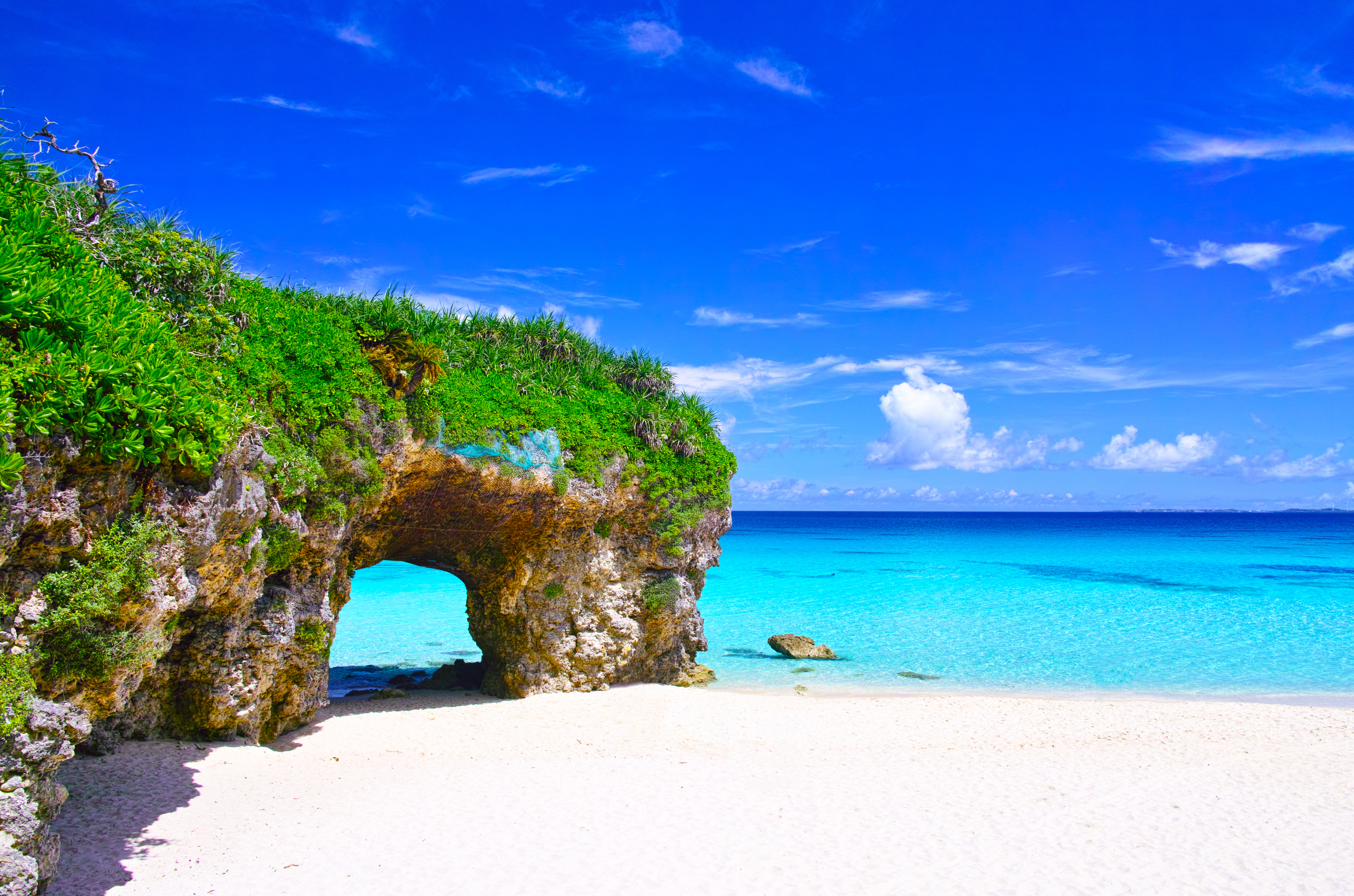 View of Sunayama Beach on Miyako Island, Okinawa, Japan, showcasing its iconic stone arch, white sand, and clear turquoise waters