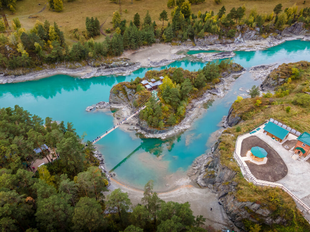 Altai Valley in Russia with lush green landscapes, rugged mountains, and a flowing river under a clear blue sky