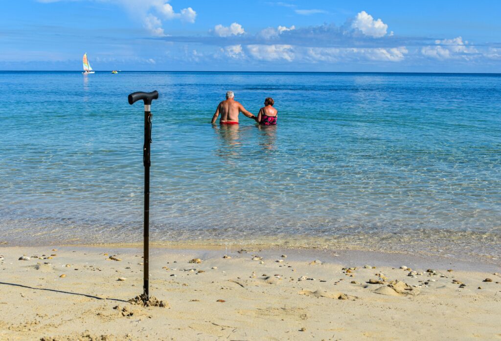 An older couple walking hand-in-hand along the sandy shore of Playa Paraíso Beach, enjoying the calm sunset and ocean views.