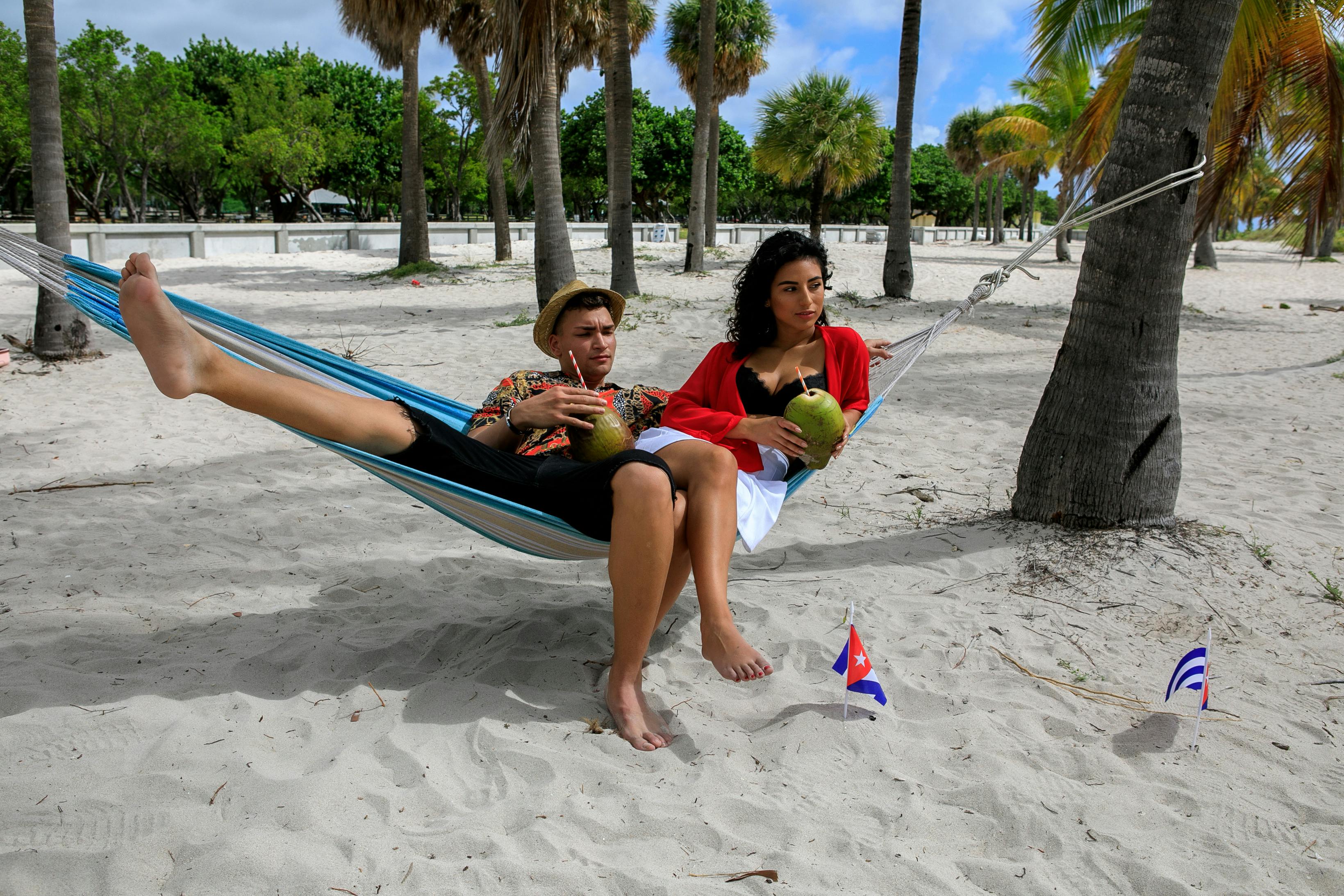 A couple sitting together on the sandy shore of Playa Paraíso Beach, enjoying the peaceful sunset with turquoise waters in the background.